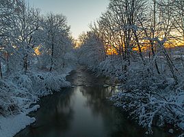 Sun setting over river in winter at Mills Riverside Park