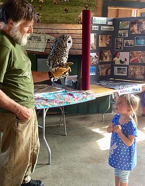 Man showing an owl to a young child